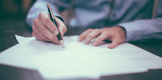 Person schreibt mit Stift auf Papier